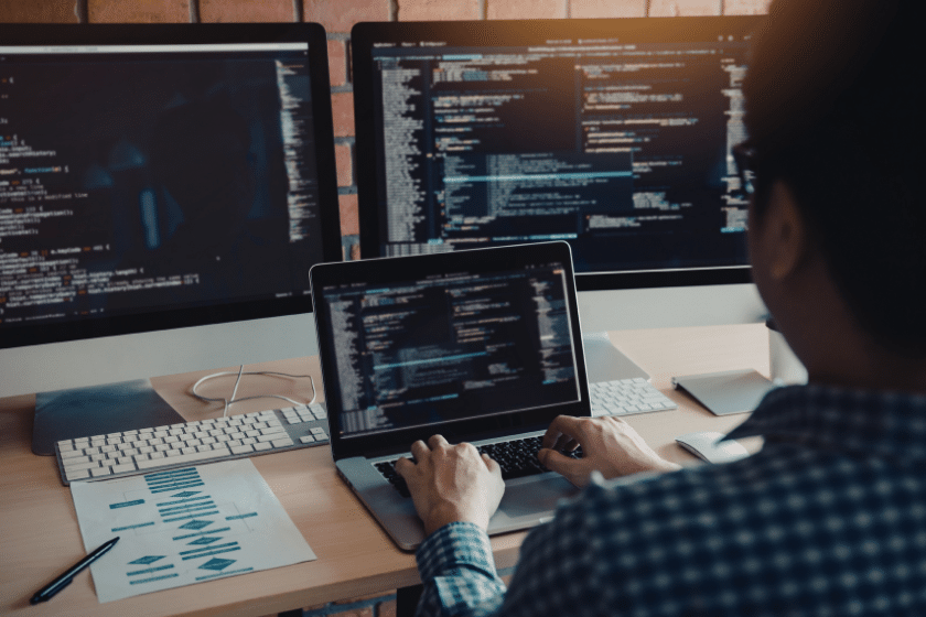 Developer al lavoro su codice su più schermi