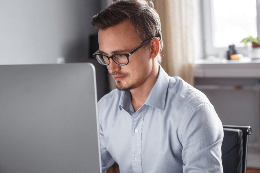 Uomo con occhiali concentrato davanti a un monitor
