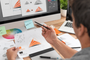 designer di un'agenzia grafica a Parma al lavoro su progetto di brand identity con schizzi, campioni colore e software di progettazione