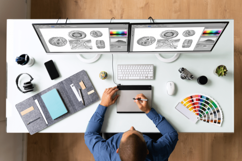 grafico professionista al lavoro con tablet grafico, doppio monitor e campionario colori pantone