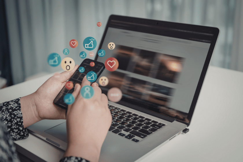 utente che interagisce con smartphone e laptop con icone social in sovrimpressione