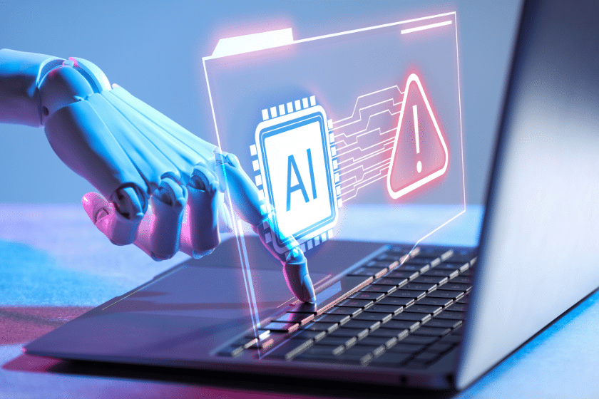 Mano robotica su laptop con avviso di rischio AI.