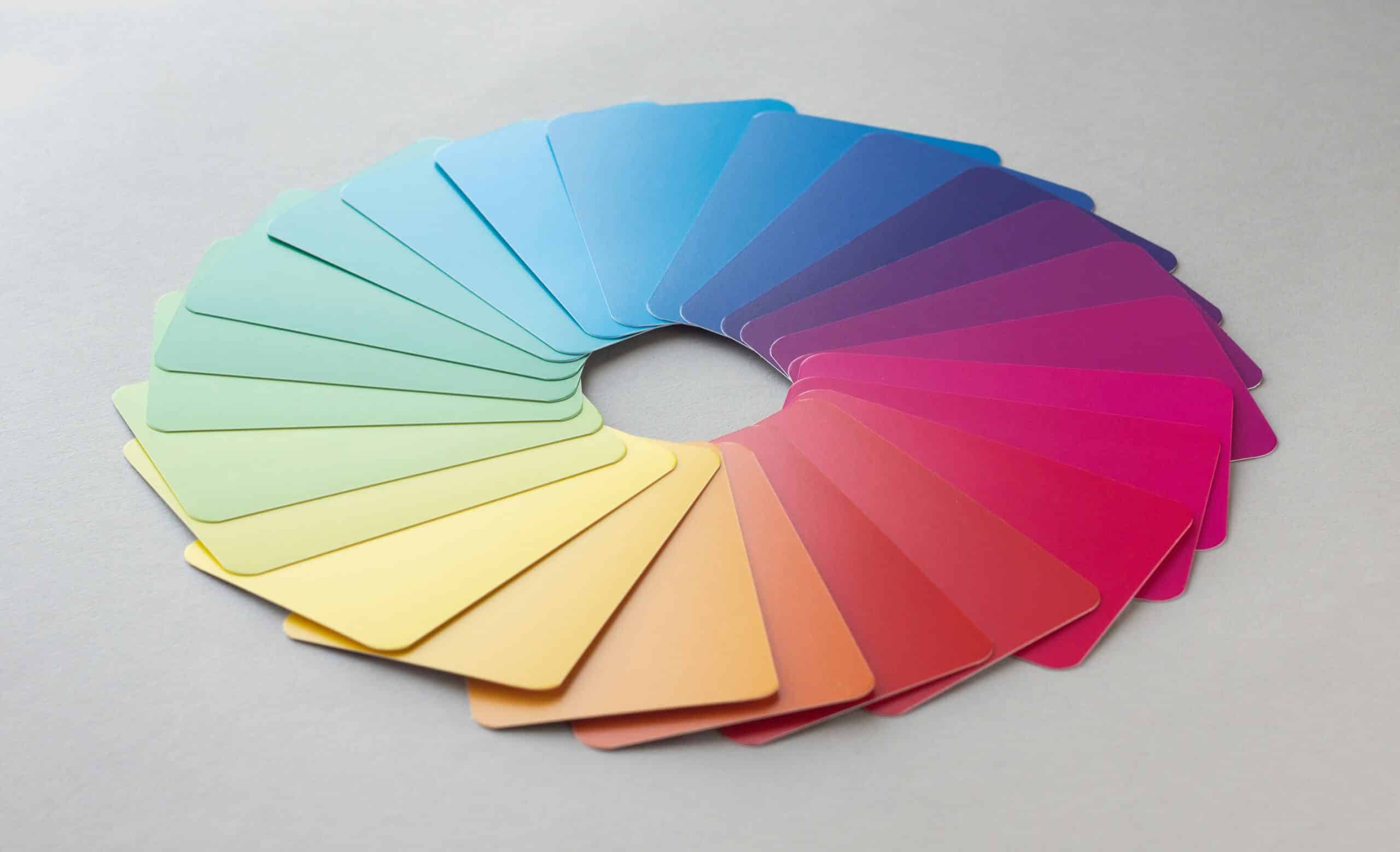 Campioni di colore disposti a ventaglio in cerchio su superficie grigia, sfumati lungo tutto lo spettro dal giallo al rosa, blu e verde
